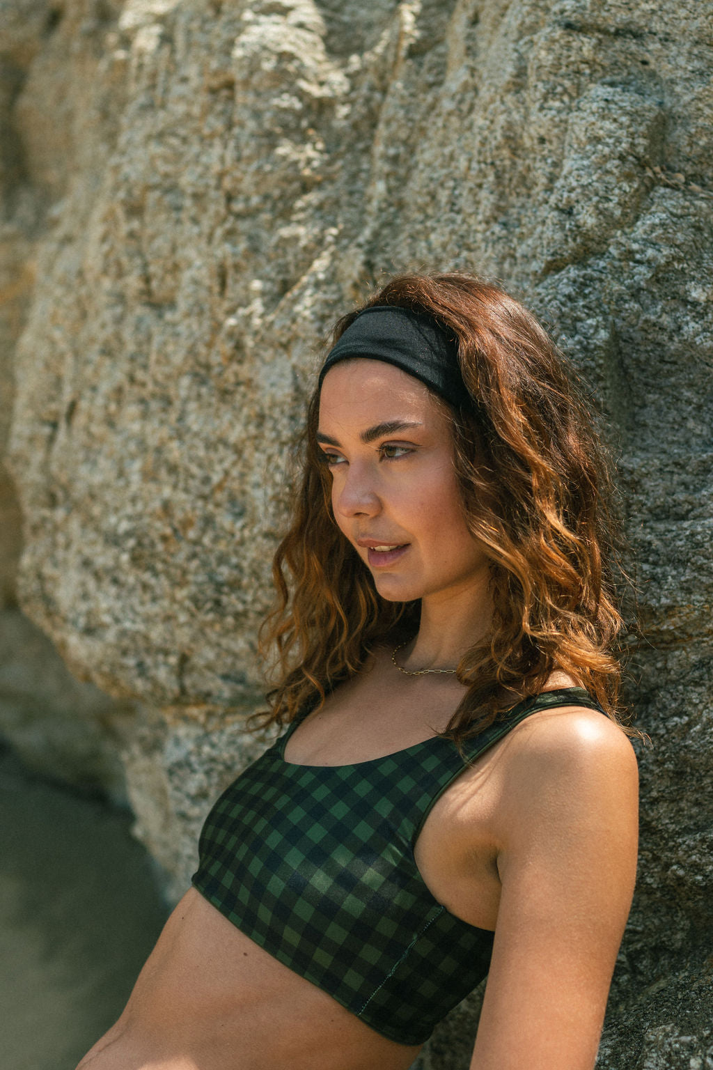 Woman wearing black headband and leaning on rock