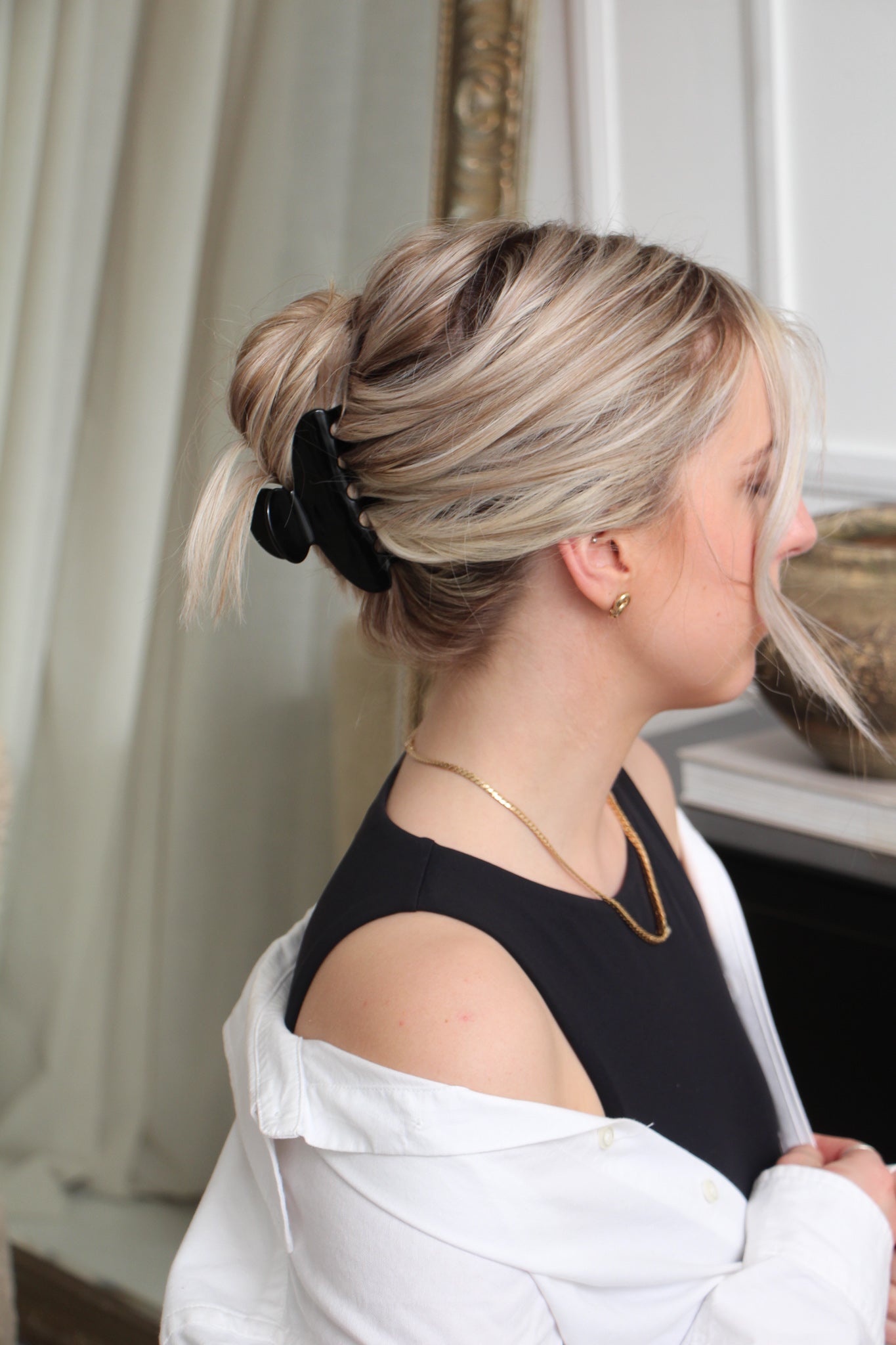 Black claw hair clip in model's blond hair. Model is wearing black tank with a white dress shirt over the shoulders. 