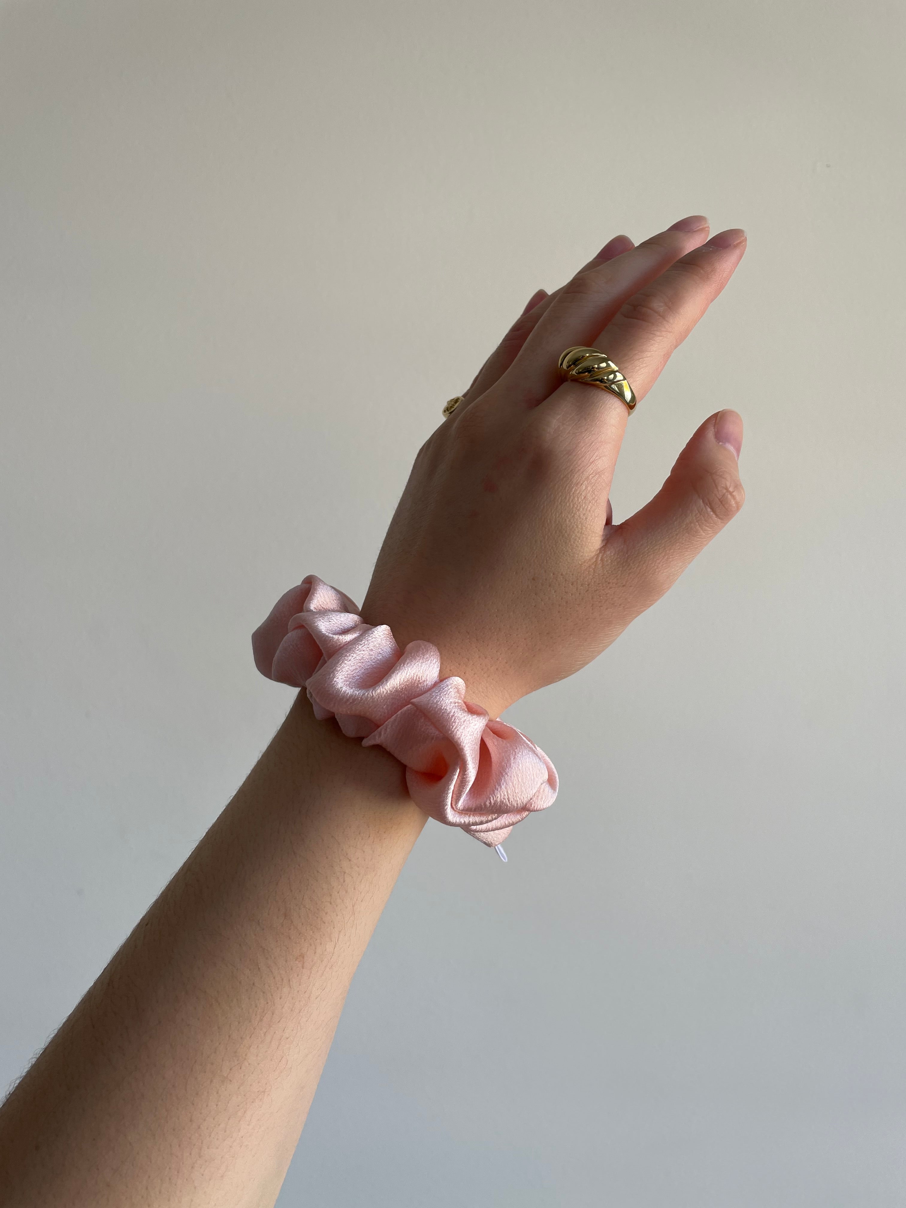 small pink silk scrunchie on model's wrist